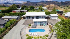 Propiedad residencial con piscina, un porche cubierto y vistas de las colinas circundantes.