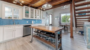 Una cocina moderna con vigas de madera, una isla central y un salpicadero azul.