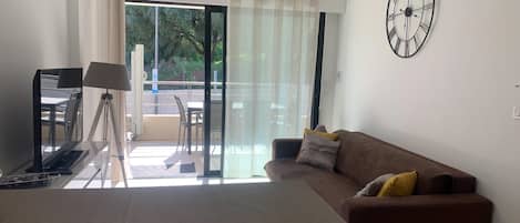 A modern living room with a sofa, a table, and a tripod lamp.