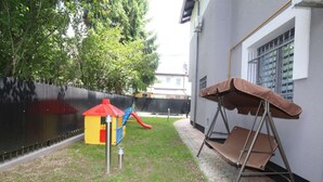 A fenced backyard with a play structure, a swing set, and a paved walkway. - Apartment Azi, Pejton Ilidža Apartments, Sarajevo (Pejton)