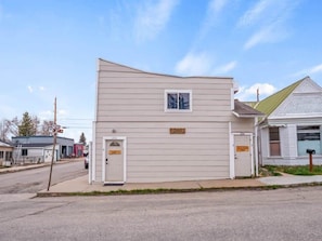 Stylish two-story building with a door and a window, situated on a street corner.