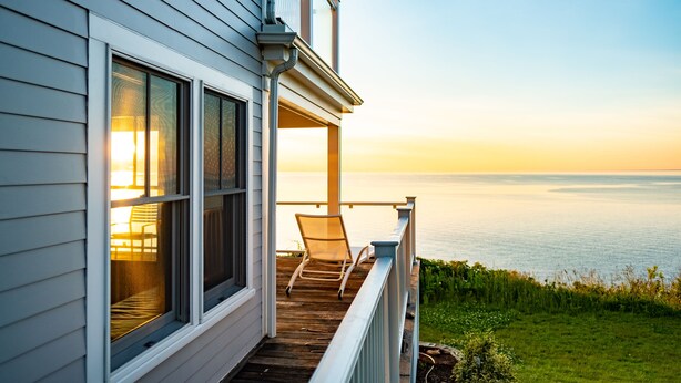Terraza de madera con una silla, con vista a un cuerpo de agua al atardecer.