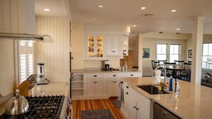 Una cocina moderna con armarios blancos, una estufa a gas y una isla grande con un fregadero.