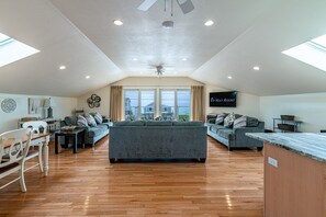 A spacious living area with a high ceiling, large windows, and a view of the outside. - Top Mast Resort- Shore House! Beach, Pool, Housekeeping and more!  (North Truro)