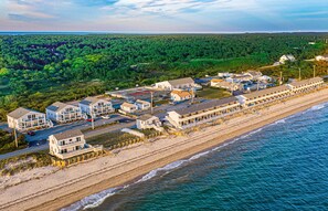 A coastal hotel with multiple buildings, a beach, and a forested area in the background. - Top Mast Resort- Shore House! Beach, Pool, Housekeeping and more!  (North Truro)