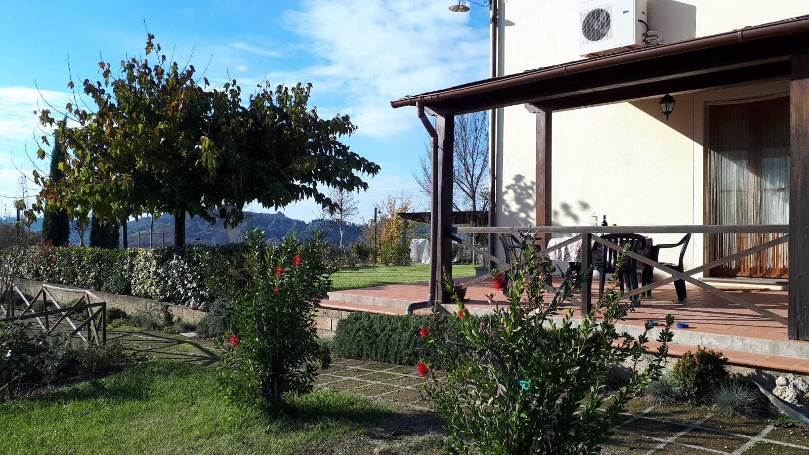 Un espacio al aire libre cubierto con una mesa, sillas, una pérgola y vistas a una cadena montañosa.
