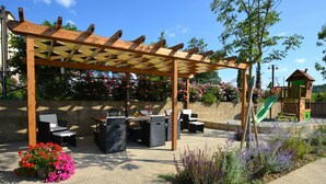 An outdoor patio area with a pergola, seating, and a children's play structure.
