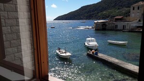 A coastal view with boats docked at a pier, clear water, and a mountainous backdrop.