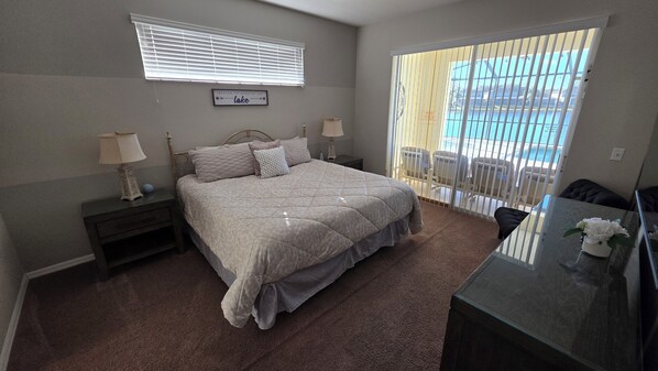 A bedroom with a bed, two bedside tables, a nightstand, a dresser, a window with blinds, and a view of a pool. - 4 Bed,3.5 Bath, 2 Masters Sf Pool / Kiddie Pool, Lakeside (Kissimmee)