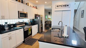 A modern kitchen with white cabinets, stainless steel appliances, and a 'KITCHEN' sign on the wall. - 4 Bed, 3.5 Bath, 2 Masters Large 30’ South Facing Pool / 8’ Kiddie Pool Lakeside (Kissimmee)