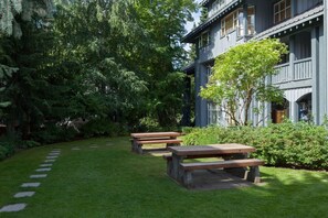 A building with a stone pathway leading to picnic tables in a lush garden.