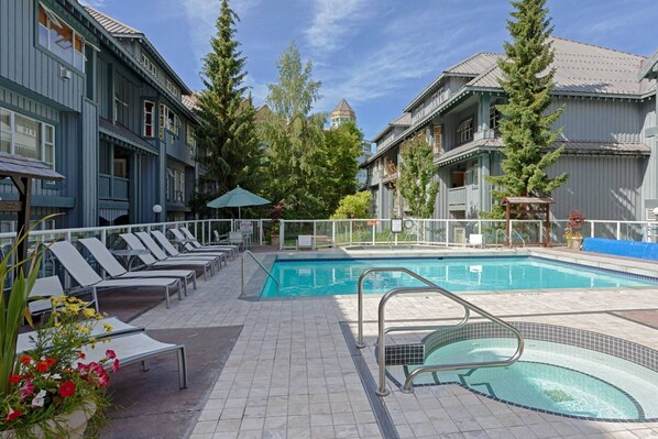 A pool area with lounge chairs, a swimming pool, and a building with a traditional architectural style.