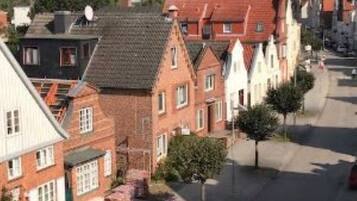A street view of a residential area with traditional European-style houses, a clear sky, and a parked car.