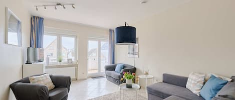 A modern living room with two grey sofas, a black armchair, a white coffee table, and a blue pendant light.