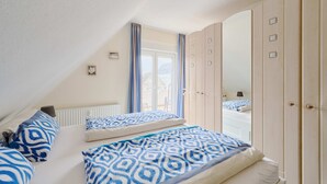 Une chambre avec deux lits, un grand miroir et une armoire.