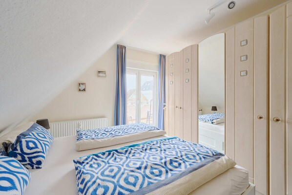 A bedroom with two beds, a large mirror, and a wardrobe. - Vacation apartment near the harbor Moba-travel (lübeck)