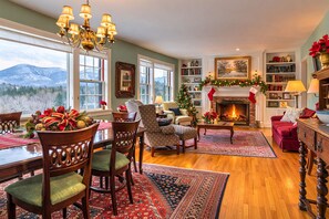A cozy living room with a fireplace, a dining area, and a view of mountains. - Ski season rental perfection: wood-burning fireplace, amazing view, dogs welcome (Manchester)