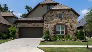 A two-story house with a stone facade, a garage, and a well-maintained lawn. - Very spacious, private location with open area, good for family travel (Sugar Land)