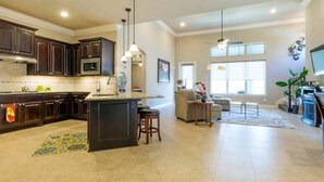 A spacious kitchen with dark wooden cabinets, a central island, and pendant lighting. - Very spacious, private location with open area, good for family travel (Sugar Land)