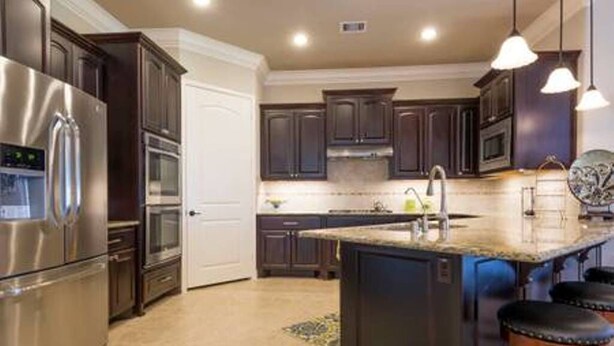 A modern kitchen with dark cabinetry, stainless steel appliances, a central island, and pendant lighting. - Very spacious, private location with open area, good for family travel (Sugar Land)