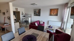 Ein modernes Wohnzimmer mit Essbereich, einem roten Sofa und einem Fernseher.