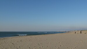 Une vaste plage de sable fin, avec des vagues douces et un ciel bleu dégagé.