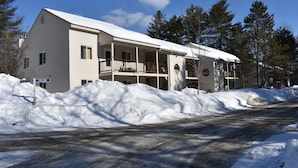 Um edifício de dois andares com varanda e varanda coberta, rodeado por neve.
