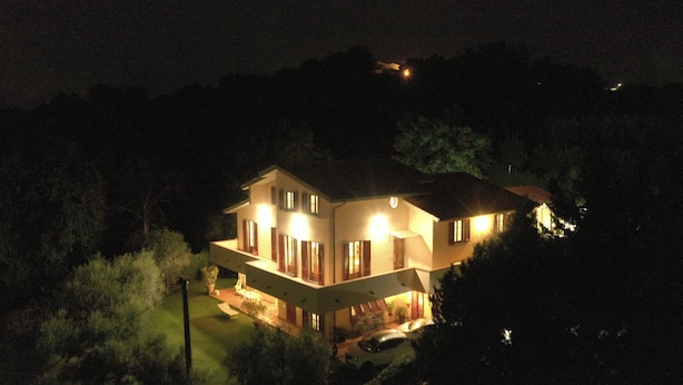 Une maison à deux étages avec un balcon, entourée de verdure.