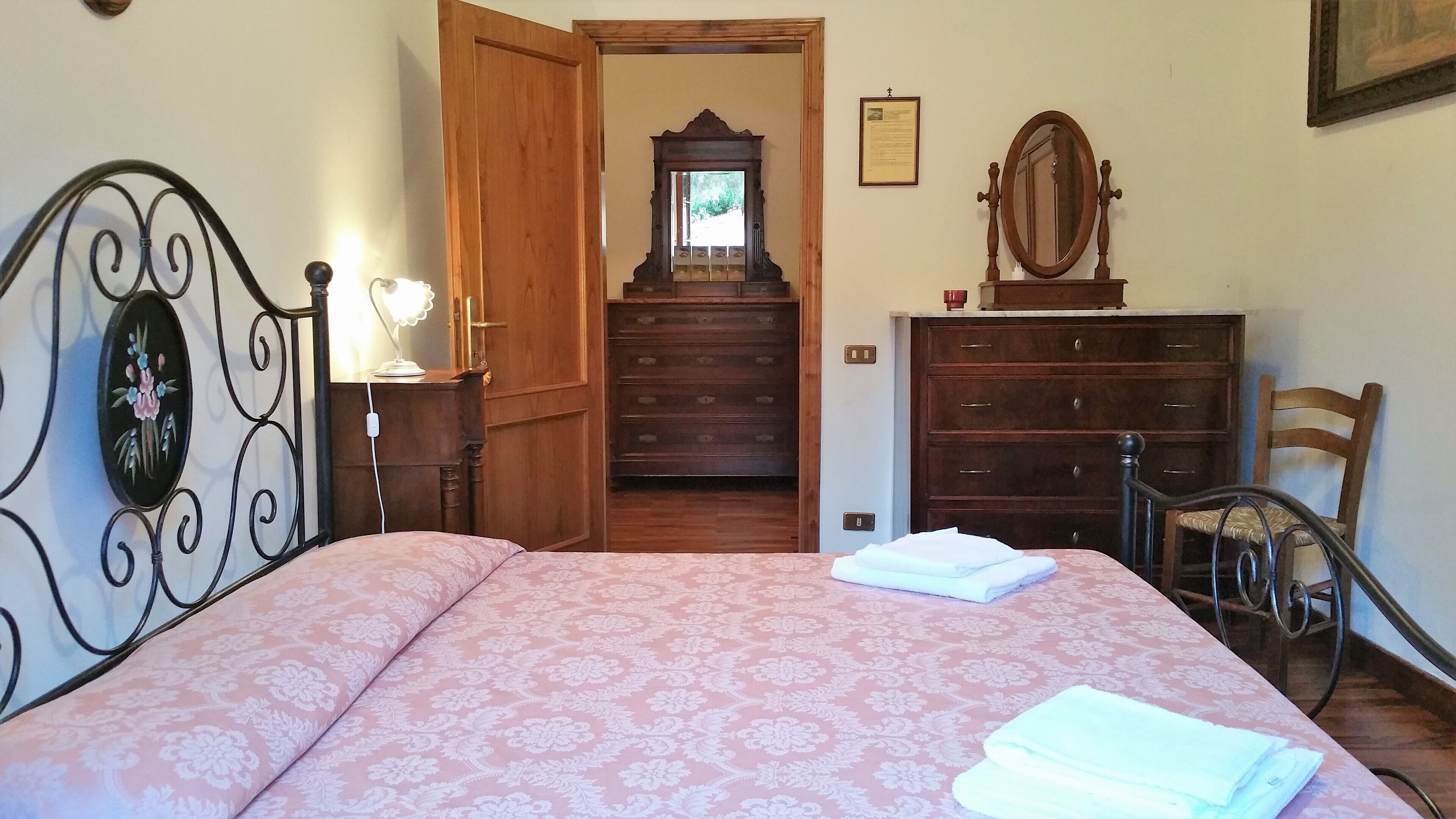 Une chambre à coucher comprenant un lit, une commode, une chaise et une armoire en bois.