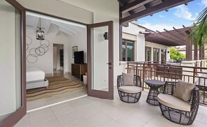 Um apartamento moderno com varanda, sala de estar com sofá e TV, e quarto com cama e decoração na parede.