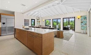 Cozinha ampla com uma ilha grande, armários de madeira e design de teto moderno.