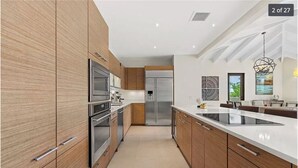 A modern kitchen with wooden cabinets, stainless steel appliances, and a large island. - Villa Mango - Bahia Beach Resort, Luxury 4 bed / 4 bath Penthouse in St Regis Bahia Beach Resort (Herreras)