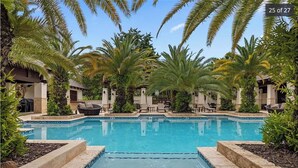 A swimming pool surrounded by palm trees and lounge chairs, with a clear blue sky above. - Villa Mango - Bahia Beach Resort, Luxury 4 bed / 4 bath Penthouse in St Regis Bahia Beach Resort (Herreras)