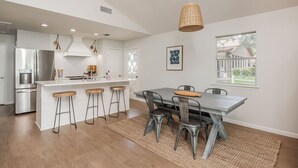 A modern kitchen with a central island, bar stools, and a dining table with chairs. - Peaceful Lake Granbury Retreat - Private Dock (Granbury)