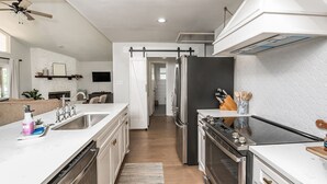 A modern kitchen with a central island, stainless steel appliances, and a sliding barn door. - Peaceful Lake Granbury Retreat - Private Dock (Granbury)