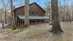 Een houten chalet met een groen dak, omgeven door bomen.