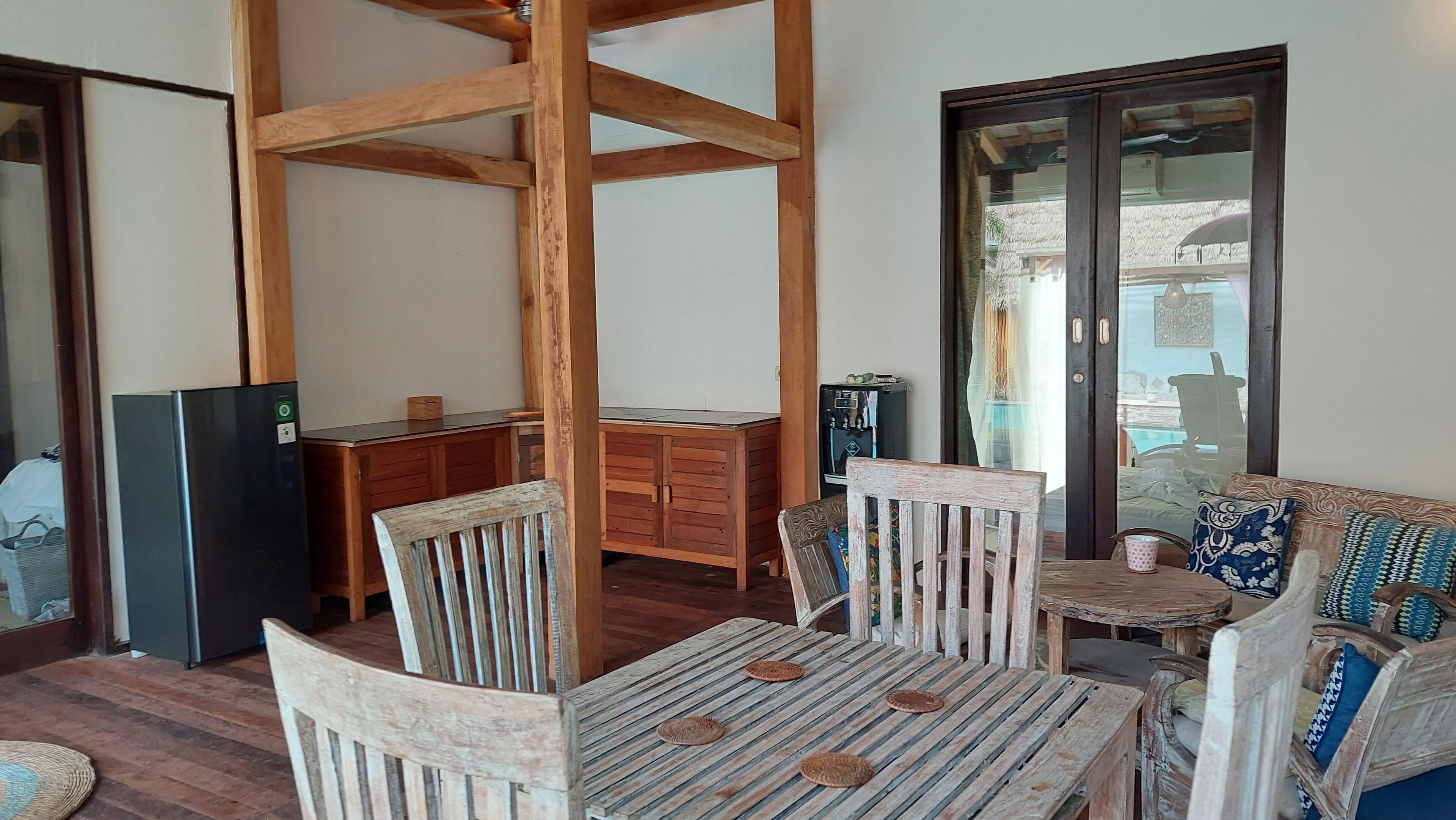 Un coin repas rustique en bois, avec une table et des chaises, un réfrigérateur et un distributeur d’eau.