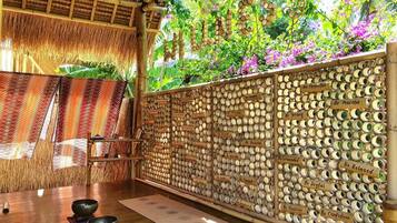 A room with a bamboo wall displaying motivational phrases, a thatched roof, and a view of lush greenery.
