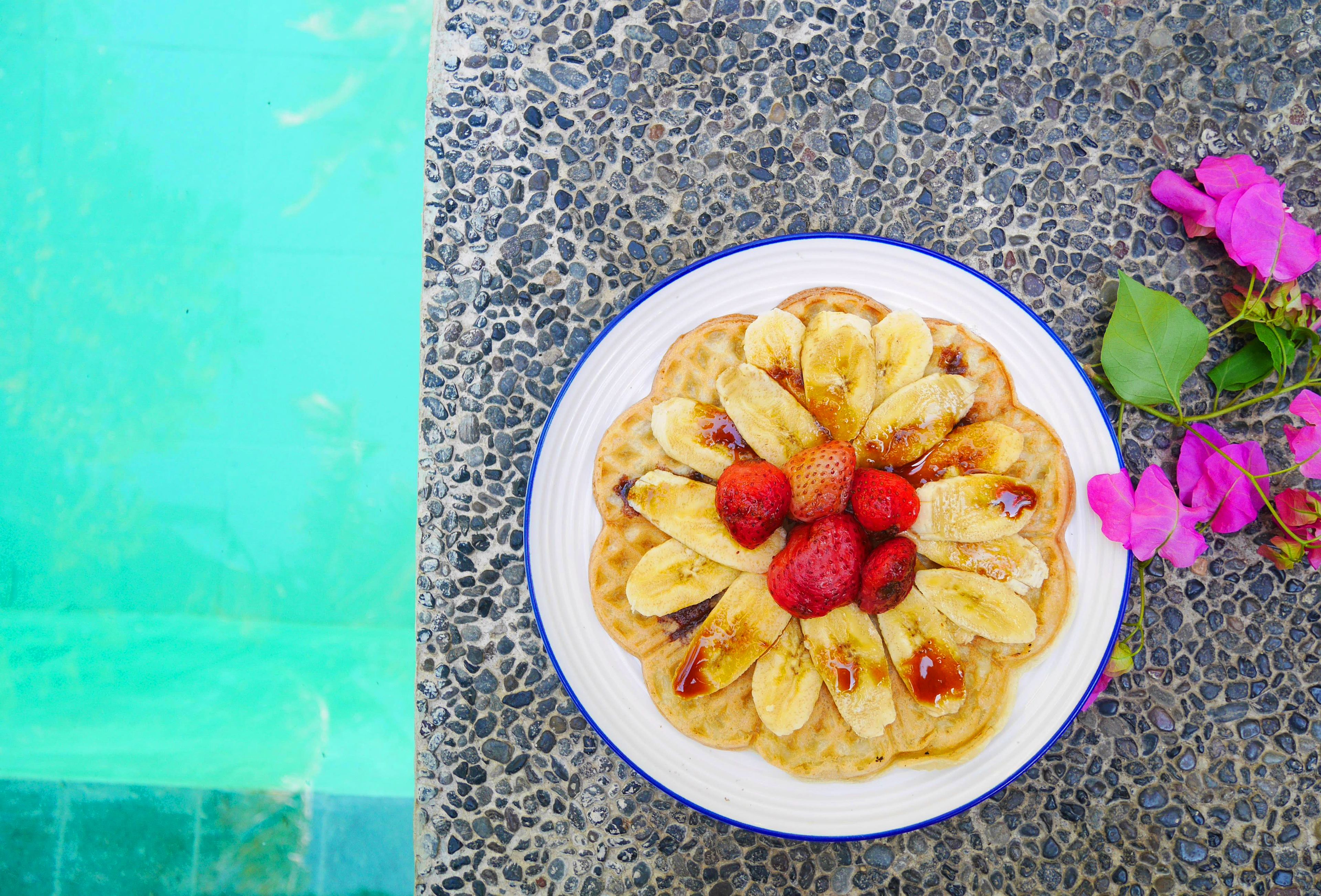 A plate of fruit-topped pancakes on a textured surface.