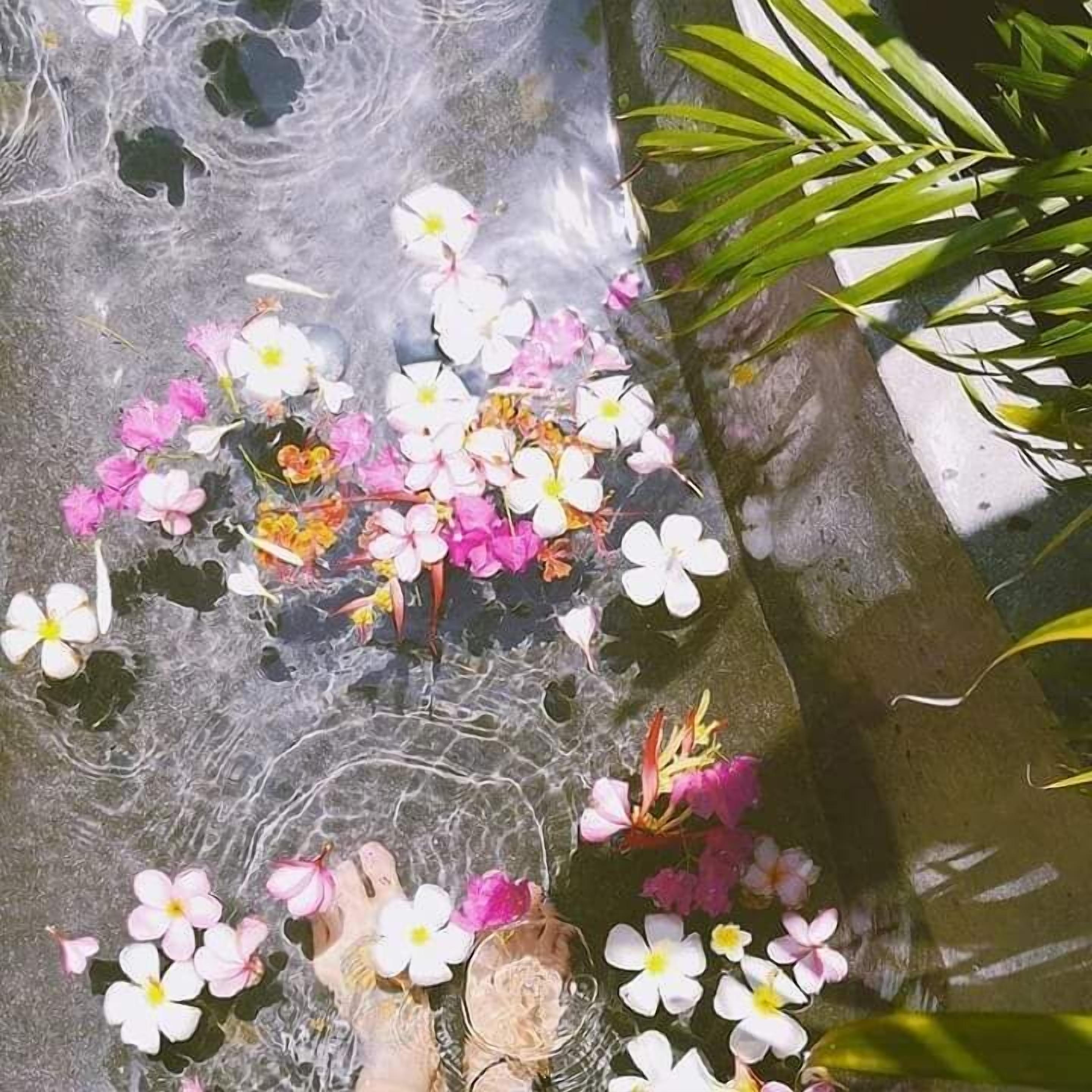 A stone surface with water and flowers.