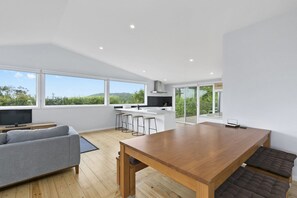 A modern living space with a dining area, kitchen, and seating. - Len's Place (Lorne)