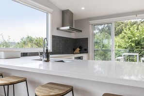 A modern kitchen with a large island, a gas stove, and a built-in oven.