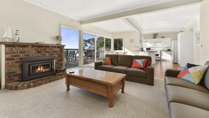A spacious living room with a fireplace, a sofa set, and a view to the outside.