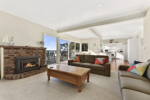 A spacious living room with a fireplace, a sofa set, and a view to the outside.