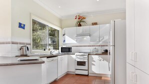 A modern kitchen with white cabinetry, a stove, microwave, and a refrigerator.