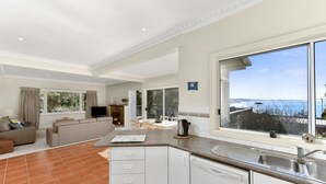 A modern kitchen with a large window, a dining area with a view, and a living room with a fireplace.