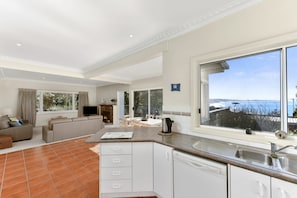 A modern kitchen with a large window, a dining area with a view, and a living room with a fireplace.