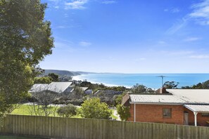 A coastal residential area with houses, a wooden fence, and a view of the ocean. - Charles (Lorne)
