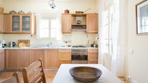Une cuisine avec des meubles de rangement en bois, une cuisinière et un grand saladier en bois posé sur la table.