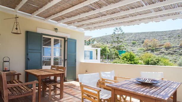 Une terrasse extérieure aménagée avec du mobilier en bois, offrant une vue sur un paysage vallonné.